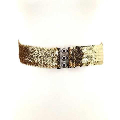 A sparkly gold sequin waist belt with a three pronged silver metal closure in the middle