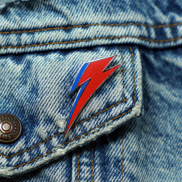 red and blue enameled silver metal David Bowie Aladdin Sane lightning bolt logo lapel pin, shown on denim jacket
