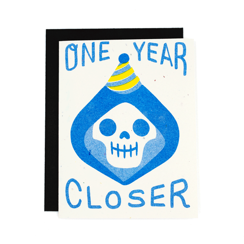 "One Year Closer" illustrated image grim reaper in a party hat Risograph printed off-white speckled paper 4.25" x 5.5" note card
