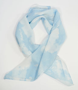 a semi-sheer chiffon scarf in a blue and white cloud print folded in a semi-circle