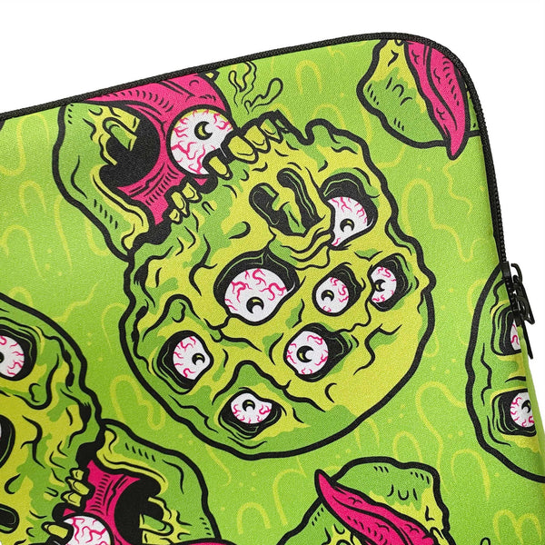 A neon green neoprene laptop sleeve with a neon green and pink multi-eyeballed drippy skull pattern. Art by Nik Scarlett. A shot showing a close-up of the art
