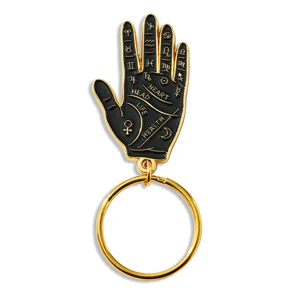 A shiny black and gold soft enameled hand pendant decorated with palmistry symbols on a sturdy gold metal keyring