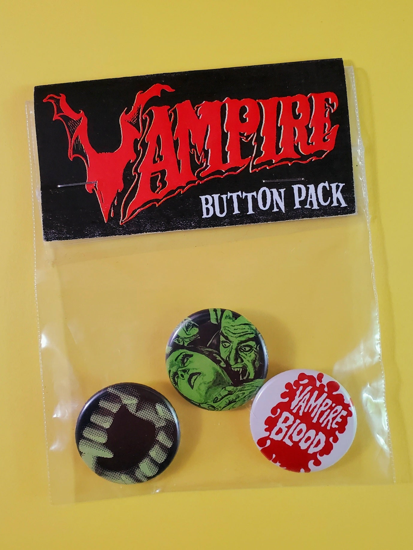 Set of three bloodsucker themed 1.25" pinback buttons, shown in plastic bag packaging with "Vampire Button Pack" illustrated header