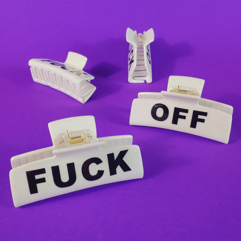 different views of a white plastic claw style hair clip with printed black “FUCK” on one side and “OFF” on the other side