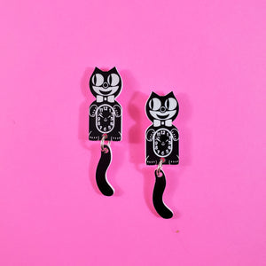 A set of drop earrings in the shape of a pair of Kit Cat clocks with dangling tails. In black
