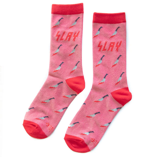 A pair of socks pink crew socks in an all-over bloody kitchen knife pattern with the word “SLAY” in a red bloody font