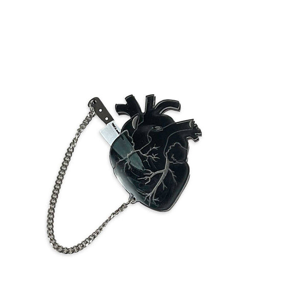 frosty translucent black anatomical heart layered over black laser cut acrylic brooch with removable tiny silver metal chain tethered black & metallic silver chef knife nestled inside