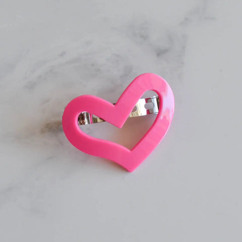 A plastic barrette in the shape of a pink stylized heart with a pinch clip fastener on its back