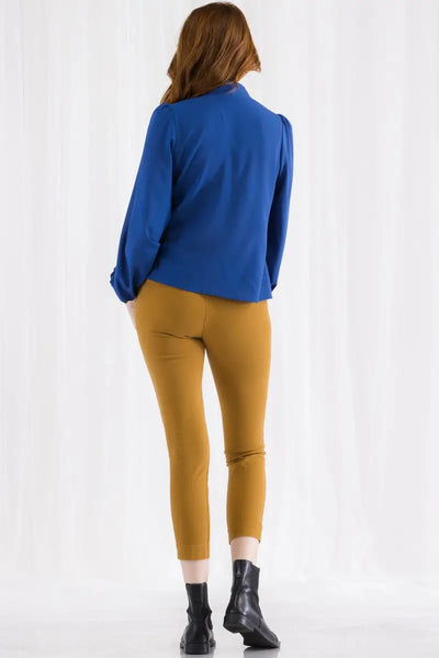 A royal blue tie neck blouse with puffed shoulders and balloon sleeves. It is a pull over blouse with elasticized gathered wrist cuffs. Shown on model from behind