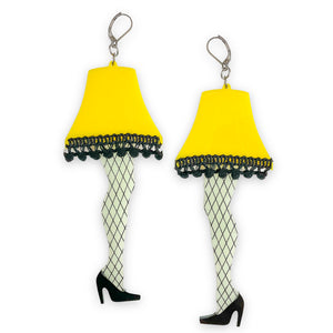 acrylic statement earrings of the iconic leg lamp from Bob Clark’s 1983 movie A Christmas Story with intricate hand-painted fishnet detail and pom-pom trim along the edge of each bright yellow lampshade