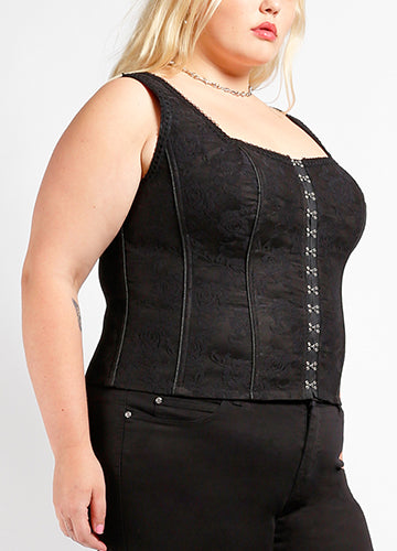 black rose pattern lace overlay on sturdy black stretch cotton corset top featuring a straight neckline, adjustable straps, channels of light boning highlighted with black cord detail, shiny silver metal hook & eye closure down the front, and grosgrain ribbon through silver eyelets lace-up back. Shown 3/4 view on model.