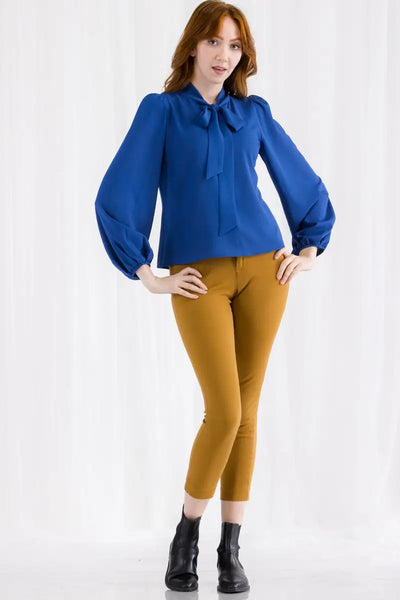 A royal blue tie neck blouse with puffed shoulders and balloon sleeves. It is a pull over blouse with elasticized gathered wrist cuffs. Shown on model 
