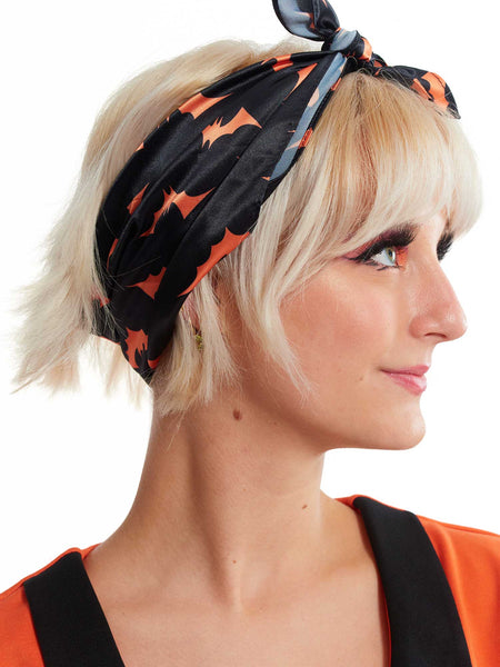 Vintage inspired satin square hair scarf in black and orange bat print. Shown tied in model’s hair 