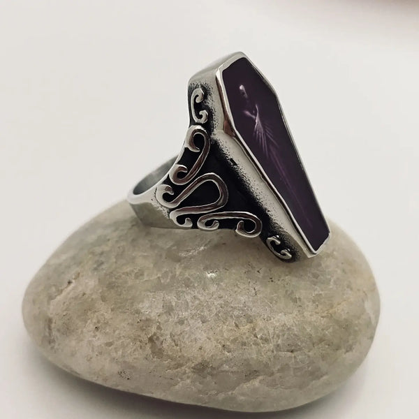 stainless steel ring depicting a vampire encased in translucent purple acrylic resin, at rest in his coffin, shown 3/4 view