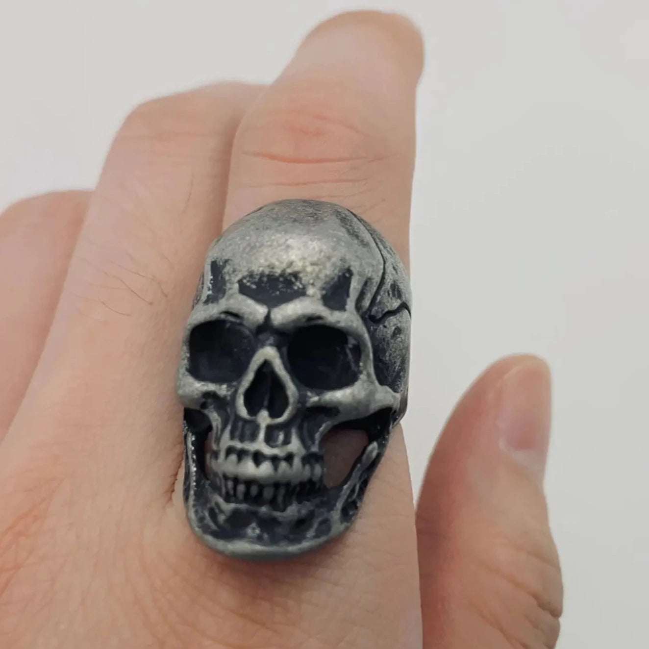 aged finish stainless steel skull ring, shown on a finger