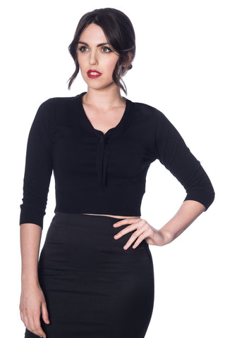 A model wearing a cropped black knit sweater with a v-neck that extends into a tie detail. It has ribbed sleeve cuffs and waist band