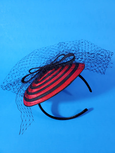 black and red spiral swirl fascinator with black bow and netting on a satin covered headband