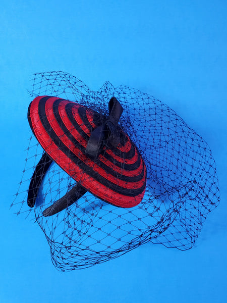 black and red spiral swirl fascinator with black bow and netting on a satin covered headband
