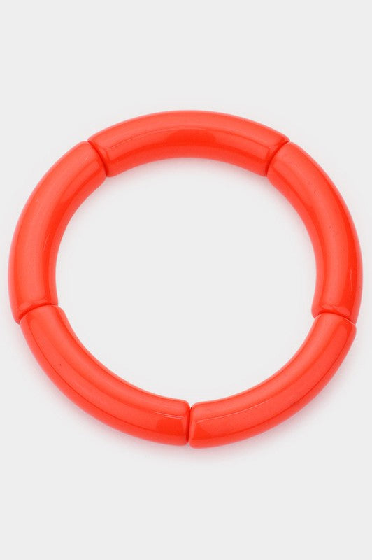 A bright orange bangle made of segments of resin strung on elastic cord 
