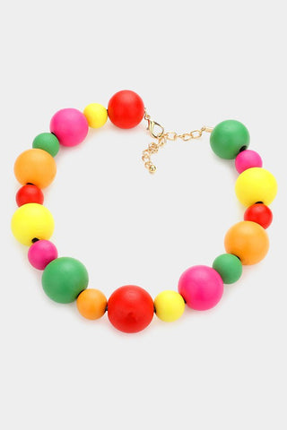 A strand of alternating wooden beads in bright and vibrant shades of red, green, yellow, and pink with an adjustable gold tone metal chain and lobster claw clasp