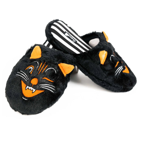 Faux fur slippers with the face of an old fashioned black cat. The cat has orange ears and an open mouth and is winking. The inner sole of the slippers has a black and white striped pattern
