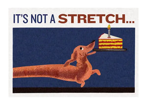 A rectangular greeting card with a dachshund holding a plate with a piece of birthday in its mouth and the message “It’s not a stretch…”