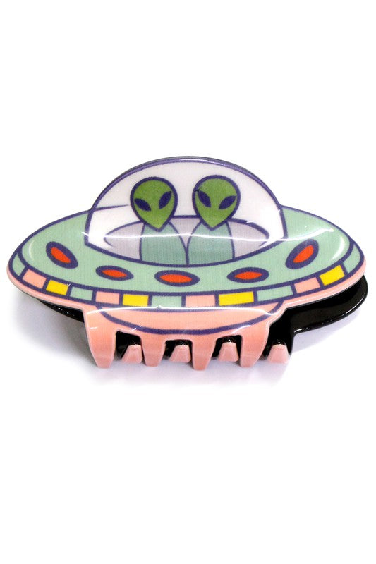A claw style hair clip with two green aliens in a pastel green, pink, and yellow flying saucer.