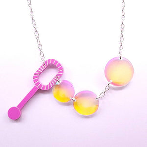 acrylic statement necklace from Sugar & Vice features a bubblegum pink bubble wand and three clear iridescent domed bubbles linked together on a shiny silver metal chain