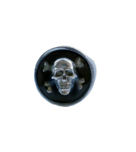 A front-facing shot of a pewter ring with a skull and crossbones in front of a black background