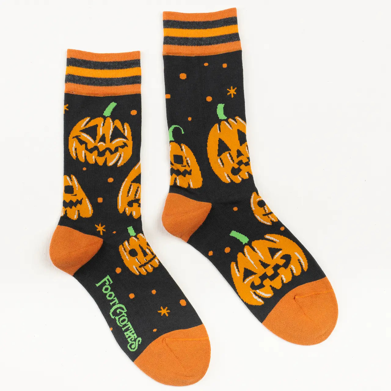 A pair of crew socks with orange and black stripes at their cuff and orange toes. The all over pattern on the socks is a group of three carved pumpkin surrounded by small orange stars