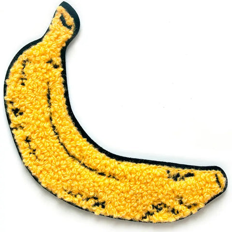 A fuzzy chenille patch of a yellow banana with black detailing and a black border