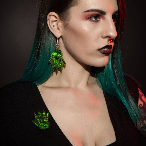 layered marbled and matte translucent green acrylic brooch depicting the claw of the Creature from the Black Lagoon, shown with matching earrings worn by model