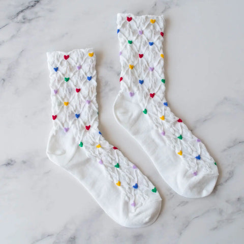 cotton knit socks in white with an allover red, yellow, green, blue, and purple heart & white flower knit-in pattern.