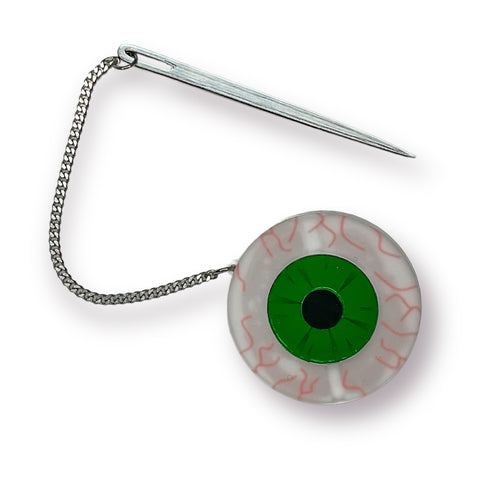 acrylic brooch in the shape of a bloodshot eye with bright green mirrored iris and a shiny mirrored sewing needle attached with a delicate curb style chain that can be placed right through the eye