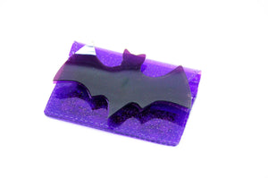 A purple glitter vinyl cardholder with a large purple vinyl bat on its fromt