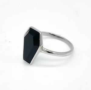 A silver stainless steel ring with a faceted black stone coffin set on a plain band