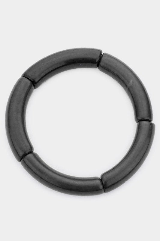 A black bangle made of segments of resin strung on elastic cord