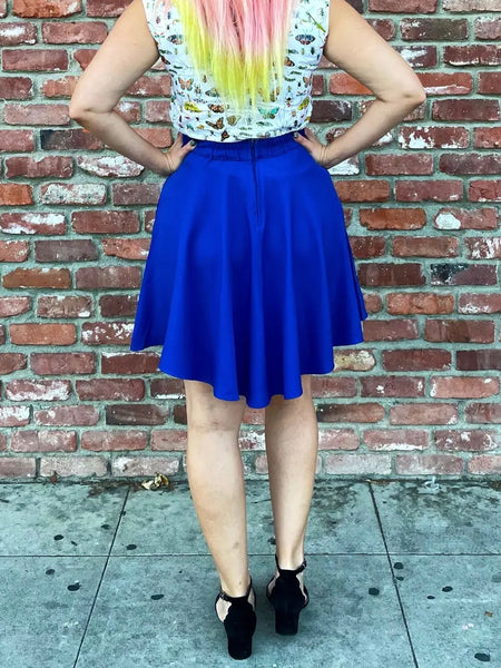 Royal blue above the knee skater skirt worn by a model wearing black high heels. Shown from the back