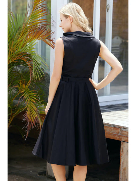 A model wearing a black sleeveless dress with a fitted shawl collar button-front bodice, removable self belt with buckle, flared just below the knee length skirt. Shown from behind
