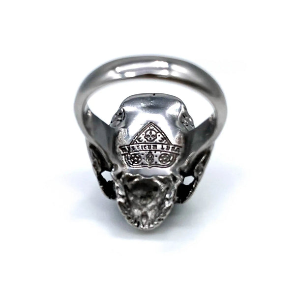A stainless steel ring of a detailed skull on a solid stainless steel band. Inside of ring is shown to display the stamped Mysticum Luna logo on the inside of the ring