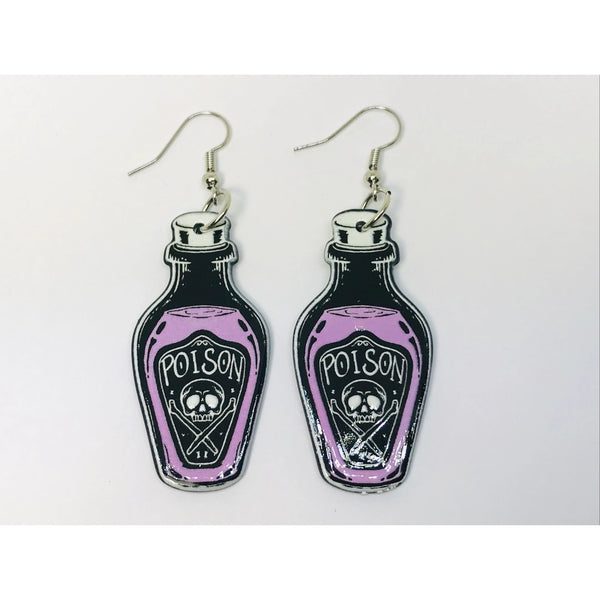 A pair of acrylic coated dangle earrings in the shape of bottles with a “Poison” label on them