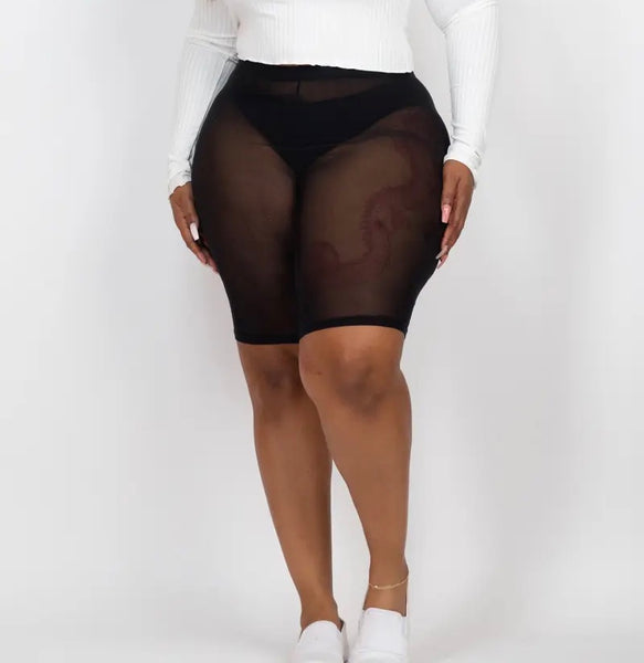 A plus size model wearing black sheer mesh bike shorts.