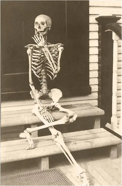 Sepia vintage photo of a skeleton posed and smoking a cigarette 