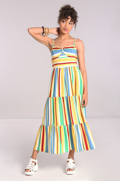 A model wearing a sleeveless sundress with horizontal red, blue, yellow, white, and seafoam stripes. It has adjustable spaghetti straps, a sweetheart neckline, bamboo ring detail at the bodice, and a three tiered long skirt