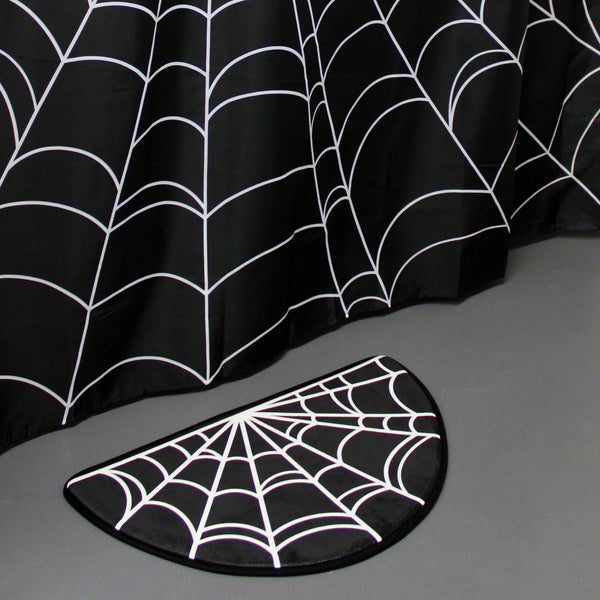 Half-round shape cushy-soft black & white spiderweb design bath mat, shown with matching shower curtain
