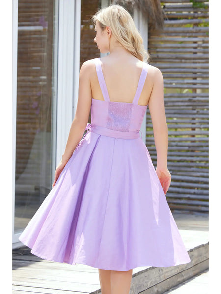 A model wearing a sleeveless with dress with a fitted sweetheart neckline princess seamed bodice with adjustable straps, removable self sash belt, swingy gathered full circle just below the knee length skirt. Shown from behind