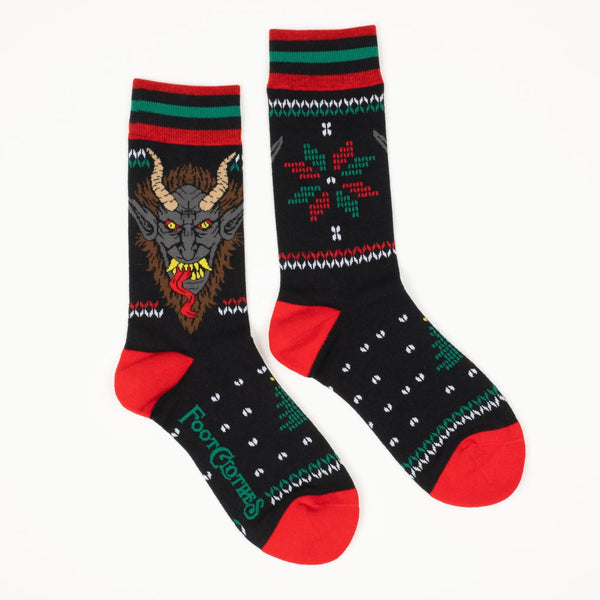 Fair Isle style pattern in red and green of holly and Christmas trees with an illustration of Krampus on soft black stretch cotton blend crew socks