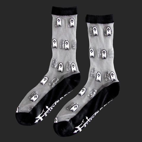 A pair of sheer socks with a black cuff, toe and heel. There is a pattern of small black and white cartoons ghosts on the sheer part of the sock.