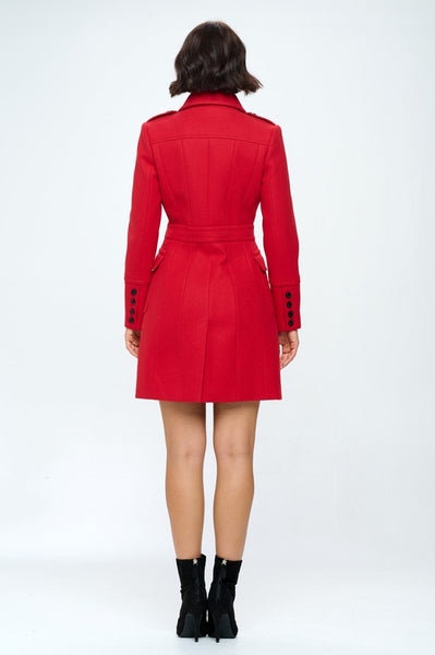 A double breasted faux wool coat in red with large patch pockets with flaps, black button details at cuffs, and flattering darting throughout. Shown on model from behind