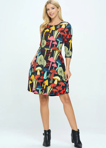 A model wearing a 3/4 sleeve knit dress that is black with a multicolored pattern of various mushrooms